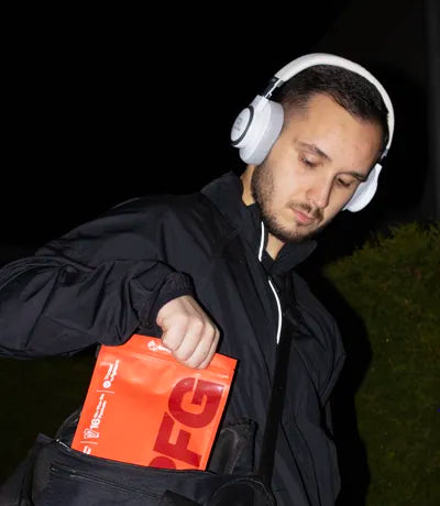 Combat sports athletes walking to the gym in a dark setting with a gym back holding RFG pouch with flow stick satchets inside.